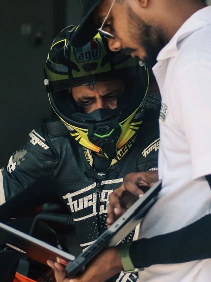 An instructor pointing out key data points on a laptop to a rider still in his gear. Immediate feedback after a session is crucial for making quick progress.