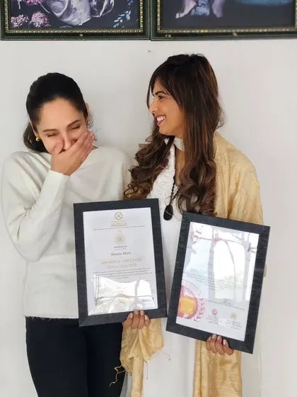 A candid, joyful moment during a certificate presentation. The journey of teacher training is intense, but it's also filled with laughter, connection, and shared success.