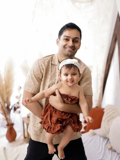 A proud father holds his smiling baby girl during a sitter session. I love including parents in milestone photoshoots too.