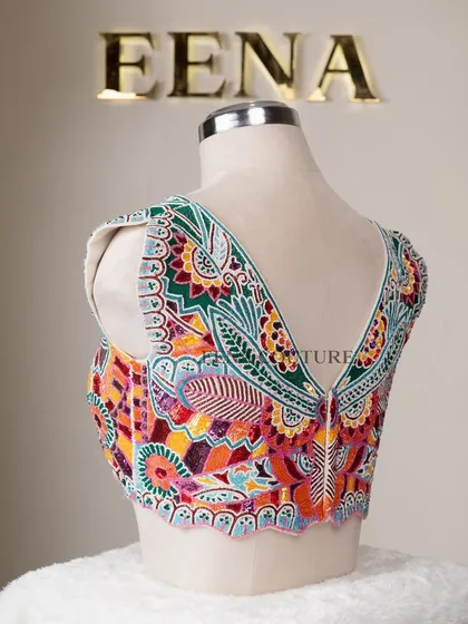 I designed this unique 'Butterfly Garden' blouse for the bride who loves color and artistry. The entire piece is covered in a vibrant mosaic of multi-colored beads and sequins, forming a stunning butterfly motif across the back.