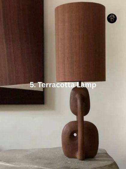 Even small accents can make a big impact. A terracotta lamp with a sculptural base introduces a warm, earthy brown tone that acts as a functional piece of art in the room.
