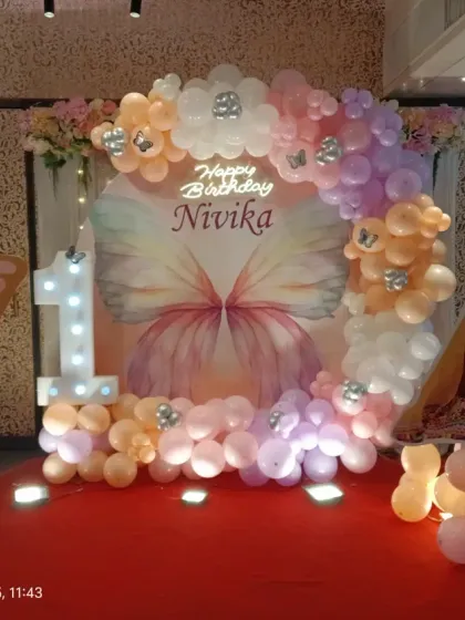 A full view of the butterfly-themed stage, showing the backdrop, balloon ring, and marquee number all working together.