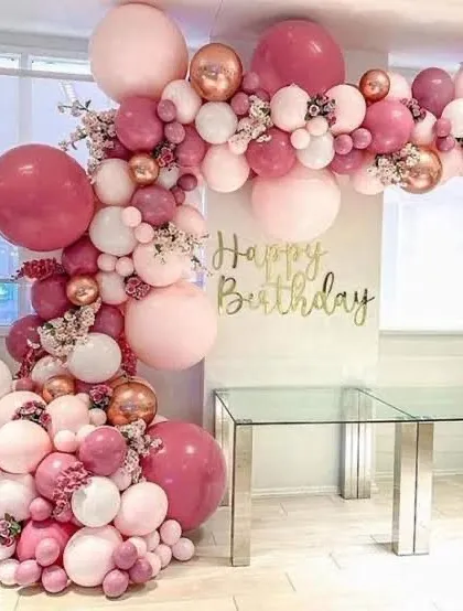 This beautiful balloon arch shows how we can create an elegant look for any celebration. The mix of deep pink, pastel pink, white, and rose gold chrome balloons, accented with delicate floral sprigs, creates a sophisticated and celebratory backdrop.