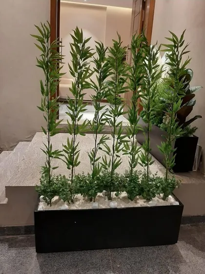 A simple yet effective divider made from artificial bamboo stalks in a long black planter, placed at the top of a set of stairs.