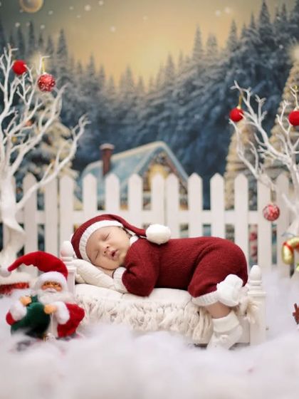 A sleeping baby in a Christmas scene. Dressed in a Santa suit, the newborn naps peacefully in a miniature bed surrounded by festive decorations.