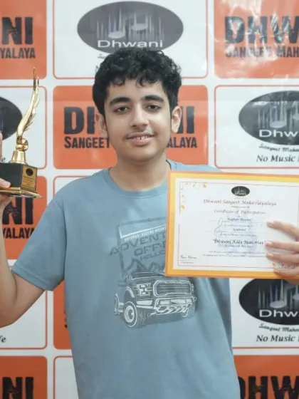 A student proudly holds his certificate and trophy.