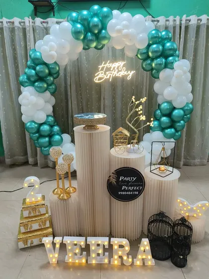 A refreshing color combination of teal and white for Veera's 2nd birthday. The balloon ring is paired with a light-up name, a number '2' prop, and other gold and black decorative elements.
