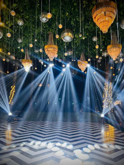 The dance floor is where the magic happens. For this beachside Sangeet in Goa, we set up a chevron-patterned dance floor under a canopy of hanging chandeliers and disco balls, with spotlights ready for the performances.