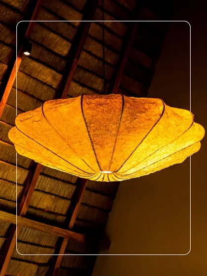 The unique, shell-shaped light fixture hanging from a thatched roof ceiling. This is an example of the small, artistic details we've added to make each space feel special.