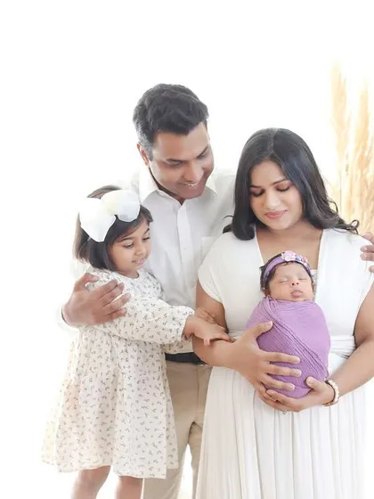 A picture of a perfect family of four. This portrait captures the joy of a growing family as they welcome their newest member, a beautiful newborn baby.