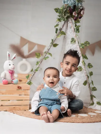 The bond between siblings is a story I love to tell. In this cozy teepee setup, the older brother’s gentle hold and the baby’s wide-eyed wonder create a heartwarming scene. I aim to capture these unposed, tender interactions that show the real connection within a family.