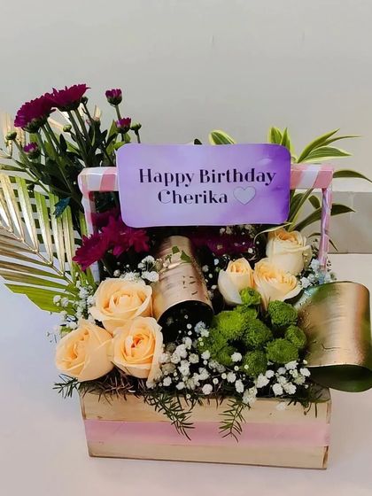 A close-up of the birthday basket with champagne, showing the beautiful peach roses and the personalized name card that makes the recipient feel truly special.