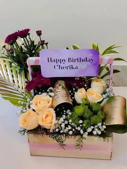 A close-up of the birthday basket with champagne, showing the beautiful peach roses and the personalized name card that makes the recipient feel truly special.