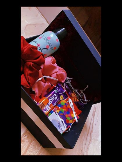 This is a great example of a mini hamper that is both thoughtful and budget-friendly. It includes a deodorant, colorful scrunchies, and some candy, all packed in a stylish black box.