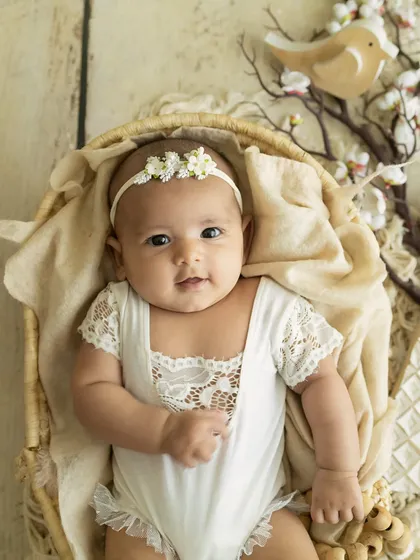 A 3-month-old angel. Dressed in a delicate white lace romper, this baby looks so serene and beautiful in our rustic, bird-themed setup.