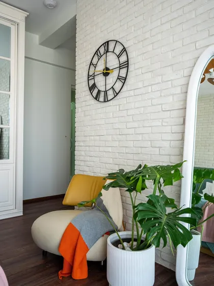 A detail shot of the reading corner in the 'Urban Oasis' bedroom, showing the large clock, wavy mirror, and comfortable seating.