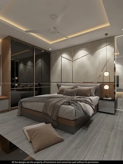 A master bedroom that feels like a luxury suite. The design includes a seating nook, a TV unit, and a walk-in wardrobe area, all in a cohesive grey and wood palette.