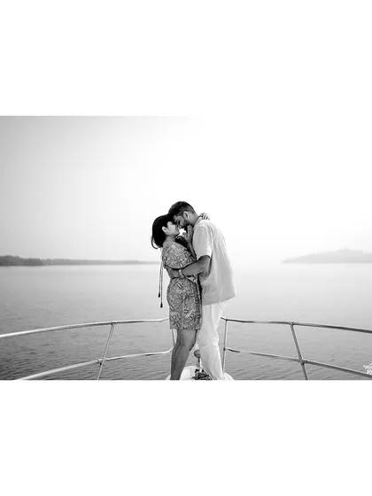 A classic black and white photo of a couple sharing a kiss on a yacht, emphasizing the timeless and romantic nature of their bond.
