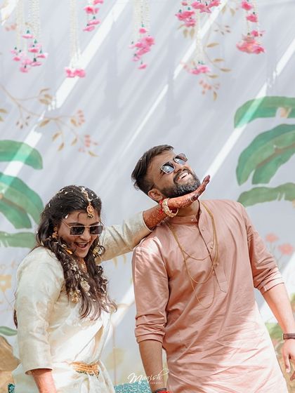 A playful moment where the bride lovingly holds the groom's chin, both of them sharing a laugh.