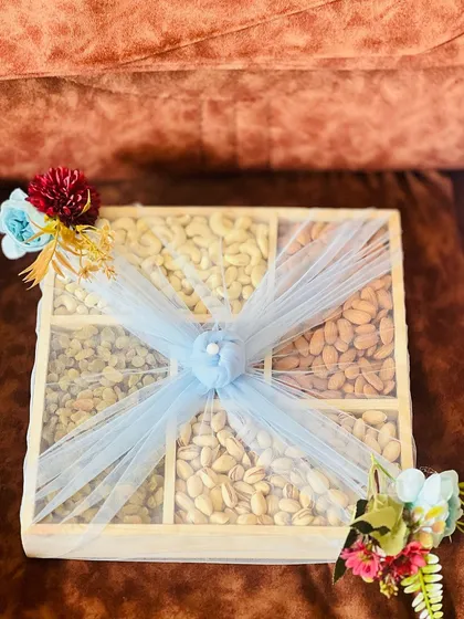 A classic and healthy gift option, this wooden box is filled with an assortment of premium dry fruits. It is elegantly wrapped with light blue net and floral accents, suitable for any occasion.