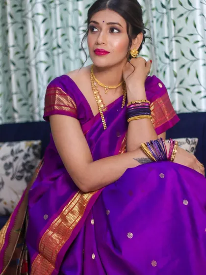 The rich purple of the Paithani saree is perfectly balanced with the radiant makeup and soft updo.