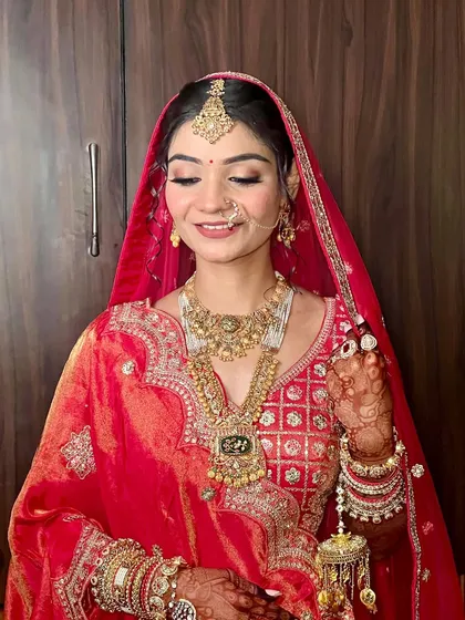 A classic bridal portrait in a traditional red and gold ensemble. The makeup features a soft cut crease on the eyes and a perfectly matched lip color to complete this timeless look.