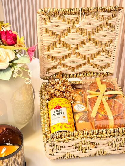 Elegance in white and gold. This handcrafted Jali basket contains festive tealight holders, Ferrero Rocher, and baked cashews, making for a sophisticated and beautiful Diwali gift for clients or family.