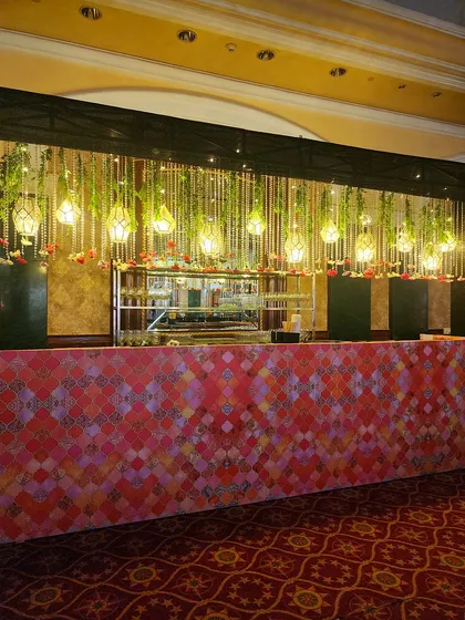 The bar for the Sufi Night was designed with a colorful patterned front and a canopy of hanging floral strings and lanterns. It seamlessly integrates into the overall theme while being a functional focal point.