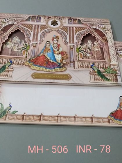 A multi-layered invitation with a die-cut frame that reveals a royal couple. The design is adorned with peacocks and intricate patterns, creating a sense of depth and elegance.