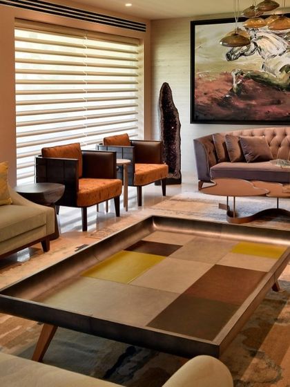 A unique coffee table with a patchwork of colored leather sits at the center of this living room. It acts as a functional art piece, tying together the diverse colors and textures used in the space.