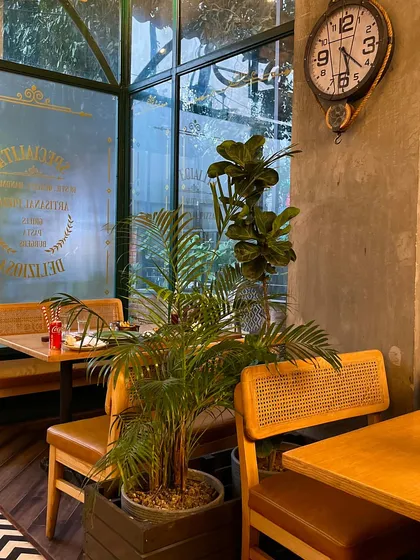Another view of the cozy interior at my Rajouri Garden café, with lush plants and warm lighting.