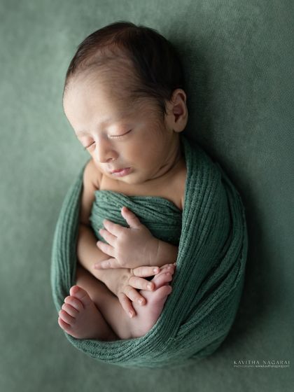 A peaceful portrait of one-week-old Aryan, wrapped in a green swaddle. The simplicity of the pose and color lets his delicate features shine.