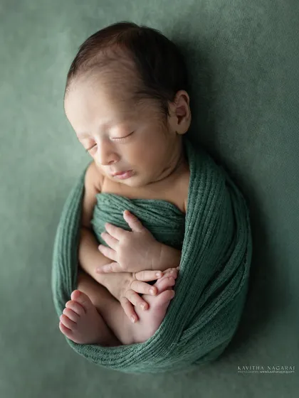 A peaceful portrait of one-week-old Aryan, wrapped in a green swaddle. The simplicity of the pose and color lets his delicate features shine.