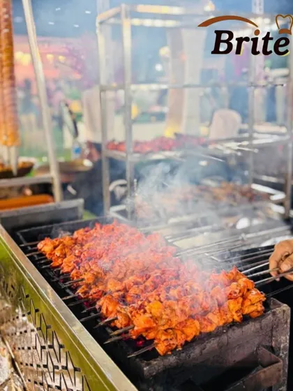 A close-up of chicken tikka skewers on the grill, smoking gently as they cook, promising a tender and flavorful bite.