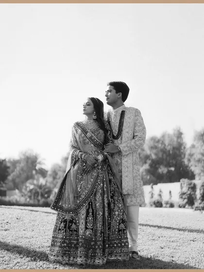 A classic black and white portrait of the couple standing in an open field. The composition is simple yet powerful, emphasizing their connection and the timeless elegance of the moment.
