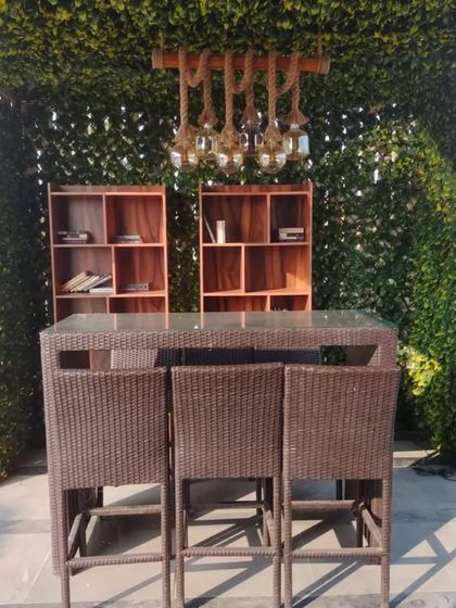 We created this cozy outdoor bar and seating area using a trellis structure covered in artificial leaves. The setup includes a high table and shelving, perfect for entertaining.