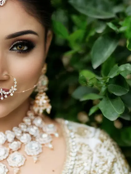 A pre-wedding gallery isn't complete without a stunning bridal portrait. This extreme close-up focuses on the intricate details of the bride's makeup, jewelry, and serene expression, set against a natural green backdrop.
