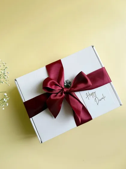 Simple, elegant, and heartfelt. This beautifully wrapped Diwali gift box with a rich maroon satin ribbon is perfect for conveying warm festive wishes to clients and employees.