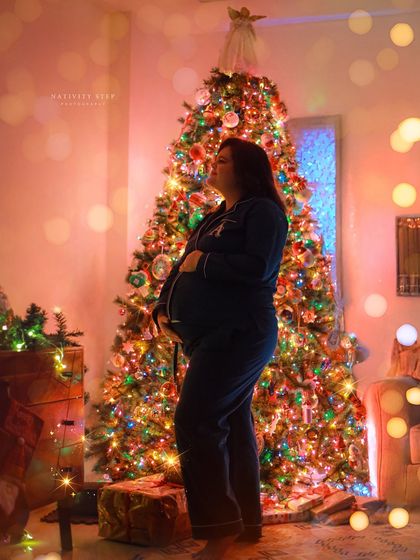 A magical solo portrait in front of a beautifully lit Christmas tree. The festive lights create a warm and joyful atmosphere.