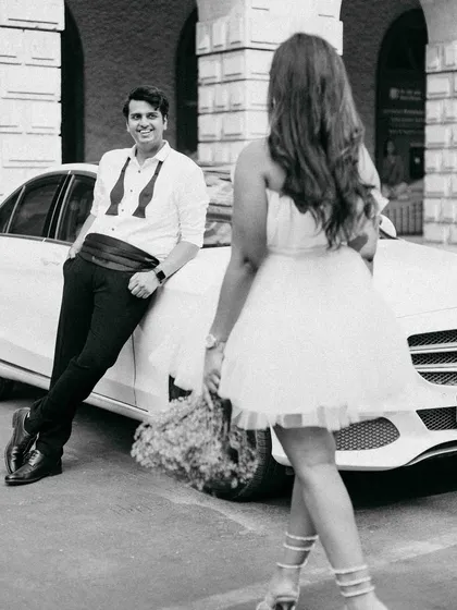 A playful, candid moment during our vintage car shoot. The way she approaches him with a smile captures a sense of fun and anticipation, adding a story to the stylish setup.
