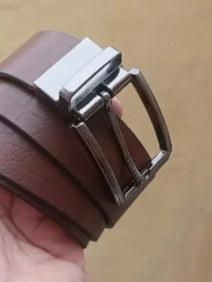 A close-up of the brown reversible leather belt, showing the buckle and texture.