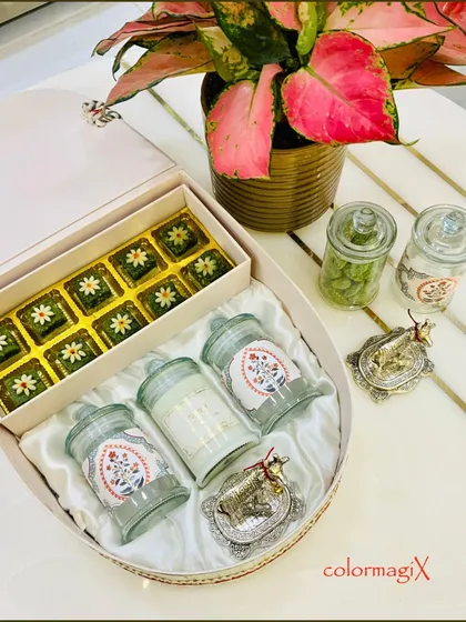 This unique teardrop-shaped box is a work of art. Lined with satin, it contains an assortment of green sweets and decorative jars, perfect for a special wedding gift.