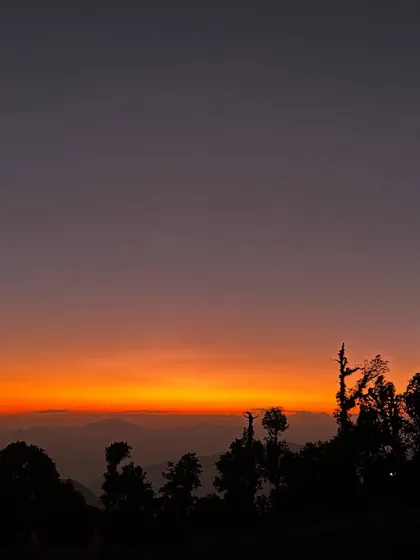 The sky on fire during the golden hour at Brahmatal. The silhouette of the trees against the vibrant sky is a photographer's dream.