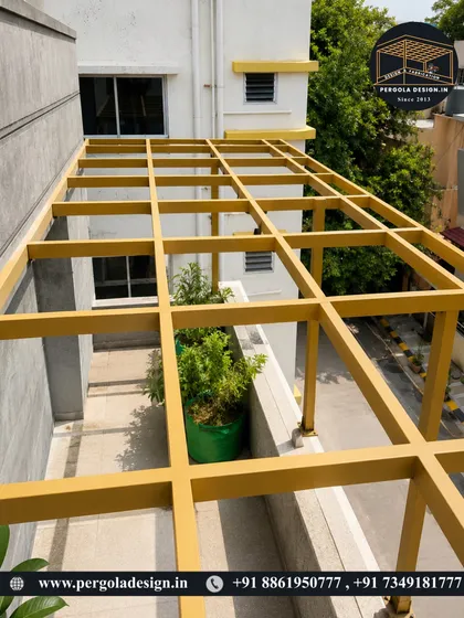 The yellow pergola frame is now fully erected on the balcony. The sturdy structure is ready for its roofing material, transforming this space into a usable outdoor lounge.