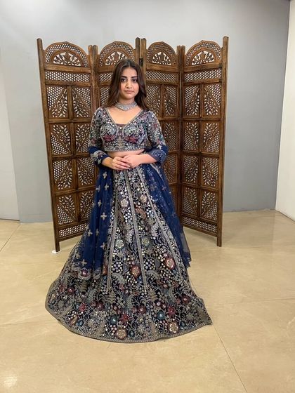 A magnificent navy blue lehenga with dense, multi-color floral embroidery. This pre-loved piece is a work of art, perfect for a grand reception.