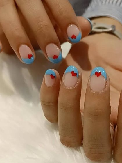 A sweet and simple design with a light blue French tip and a tiny red heart on each nail.