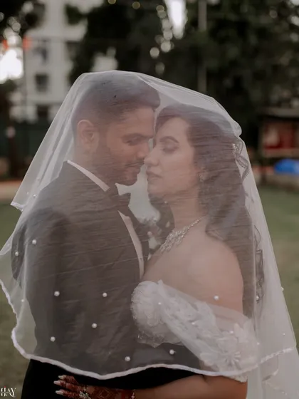 A classic Christian wedding portrait, using the bride's veil to create a soft, romantic frame around the couple. This shot highlights our ability to blend traditional poses with a touch of modern artistry.
