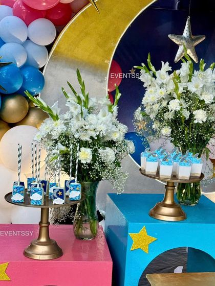 Themed juice boxes and cupcakes displayed on elegant stands with fresh flowers.