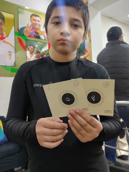 Krish, one of our young rifle shooters, holding up his practice targets. He is a dedicated student who is always eager to improve.