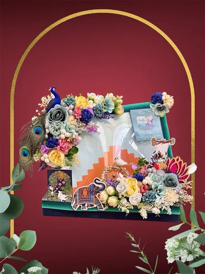 This Teej hamper is a burst of color, with a beautiful peacock, an embroidered elephant, and a mix of vibrant flowers. We designed this to elegantly display a gifted saree and other small presents.